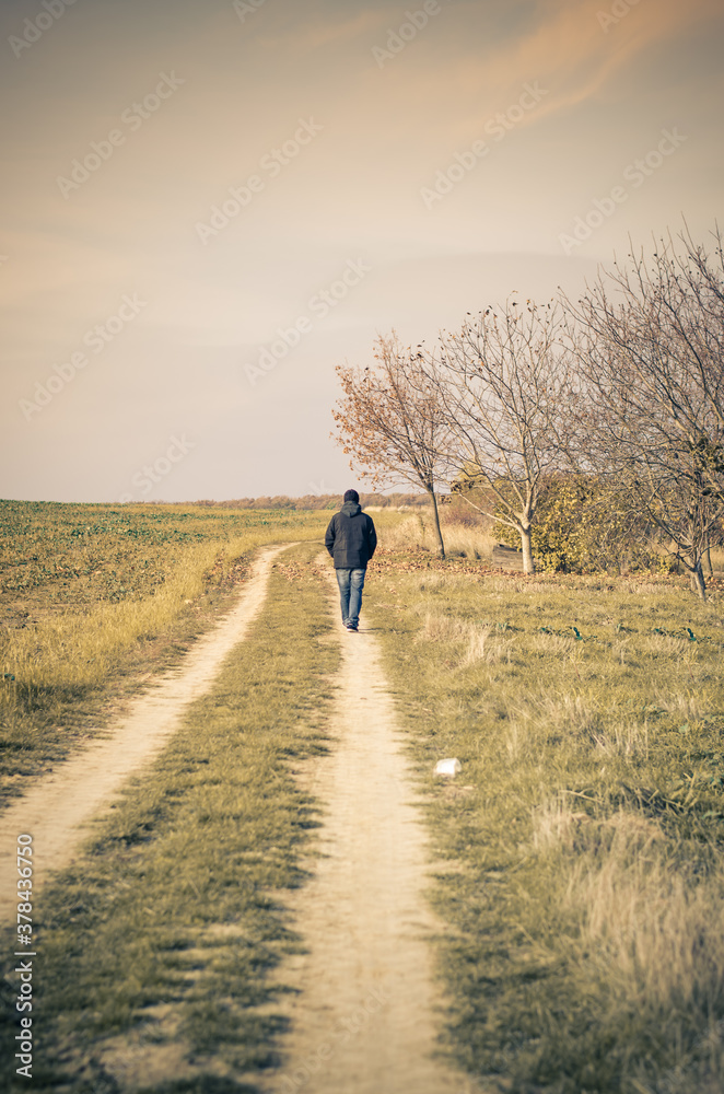 one man alone walking away on rural path one man alone walking away on rural path