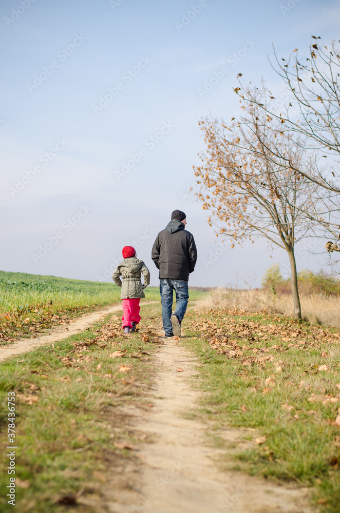 man and child walking together in autumnal colorful nature in rural path man and child walking together in autumnal colorful nature in rural path
