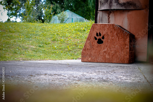 Dog kennel by the driveway with lawn and greenhouse in the background photo