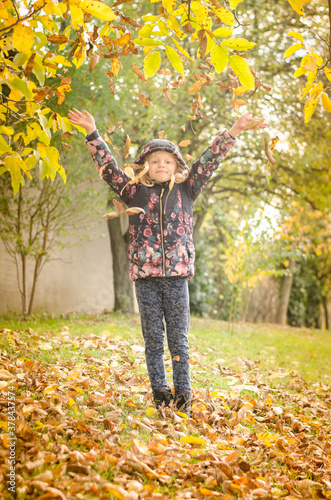 little child throwing colorful autumnal leaves