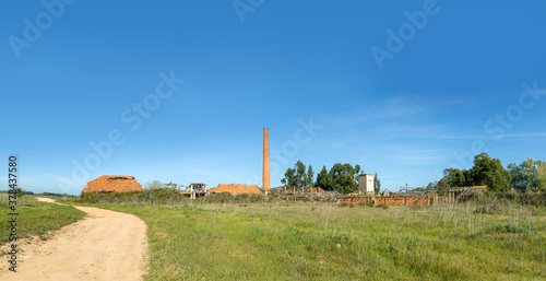 old rotten factory with damaged roof and old brick chimney in Sines, region Setubal as symbol for former industry © travelview