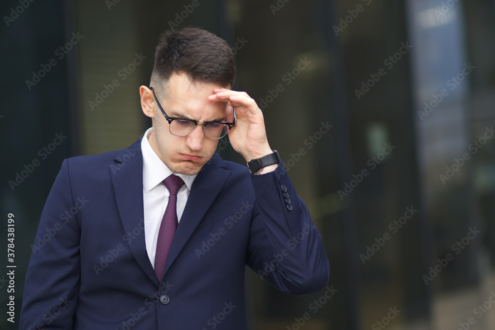 Tired, exhausted, overworked businessman in suit and glasses is holding his head with hand, suffering from headache after a hard long work. Problems at job. Tired, exhausted, overworked businessman in suit and glasses is holding his head with hand, suffering from headache after a hard long work. Problems at job.