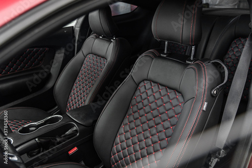 Luxury car interior with black leather seats featuring red diamond stitching. Premium upholstery and ergonomic design for a high-end vehicle.