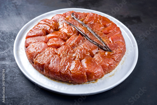 Traditional French tarte tatin with apples and vanilla offered as close-up on a modern Nordic design plate with rustic background photo