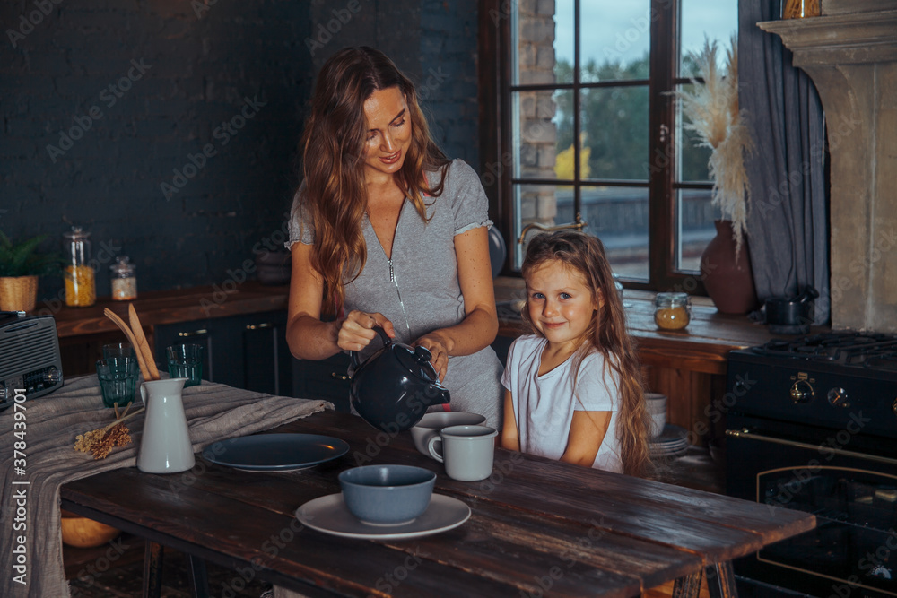 Happy loving family preparing dinner together. Smiling Mom and child daughter girl cooking and having fun in the kitchen. Homemade healthy food. Little helper in a dark kitchen interior at home Happy loving family preparing dinner together. Smiling Mom and child daughter girl cooking and having fun in the kitchen. Homemade healthy food. Little helper in a dark kitchen interior at home