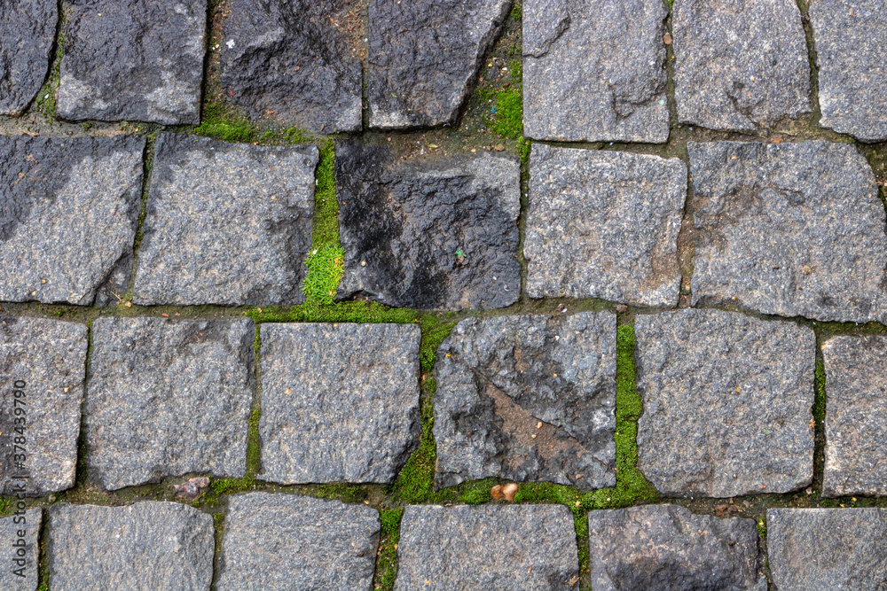Granite paving stone background of the sidewalk. Abstract background of an old cobblestone street close-up Granite paving stone background of the sidewalk. Abstract background of an old cobblestone street close-up