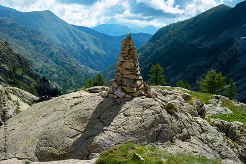 haut cairn sur un rocher et panorama sur une vallée dans les Alpes © Christophe