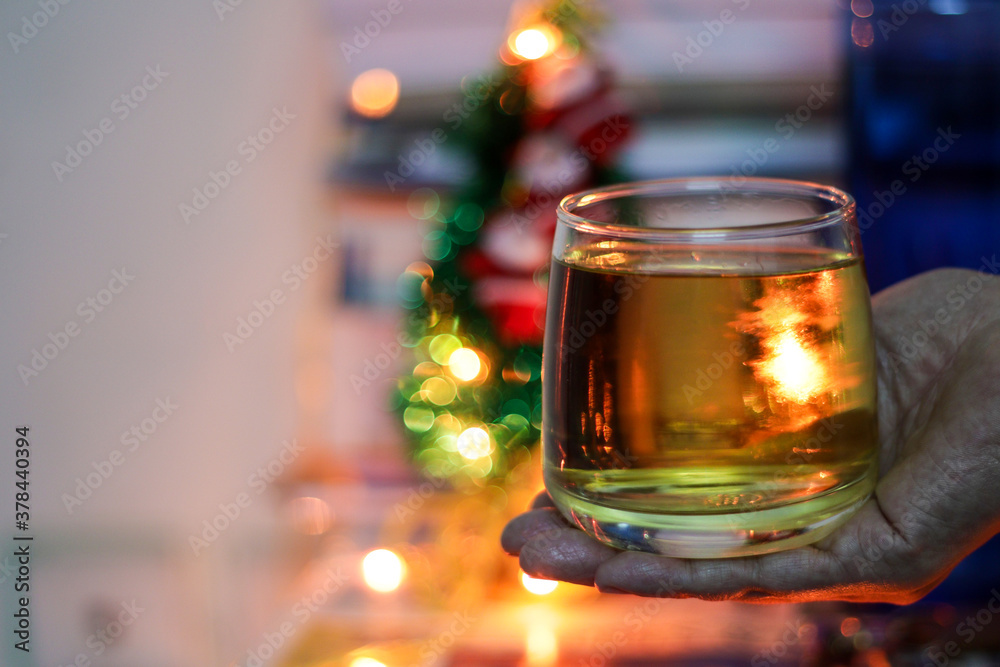 a glass of alcohol rum held in hand with background blurred bokeh lights