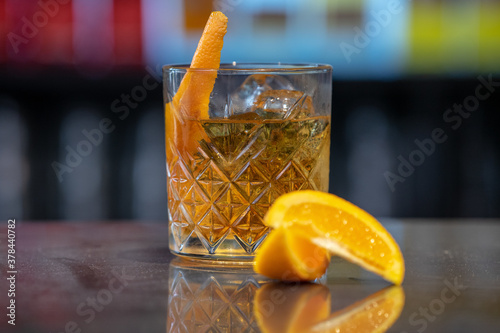 Closeup shot of a glass of iced cocktail with orange on a bar counter photo
