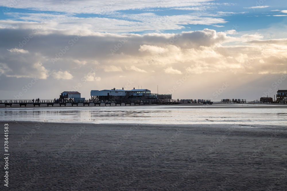 Panoramic view of stilt houses and wooden seabridge at north sea beach in Sankt Peter-Ording, Germany.