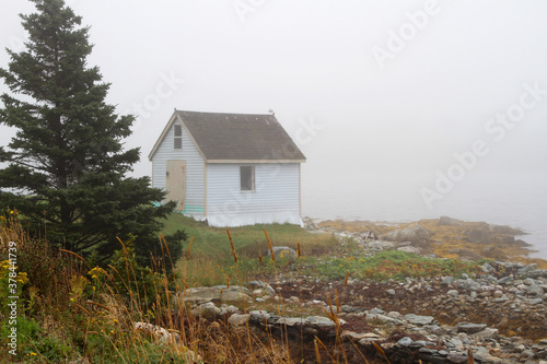 Old white shed on rocks on a foggy day