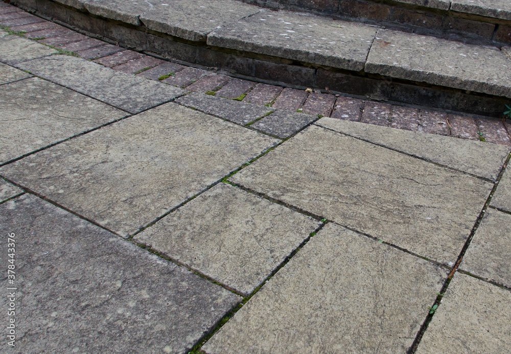 Fototapeta premium Old weather stained paving patio background with steps and bricks