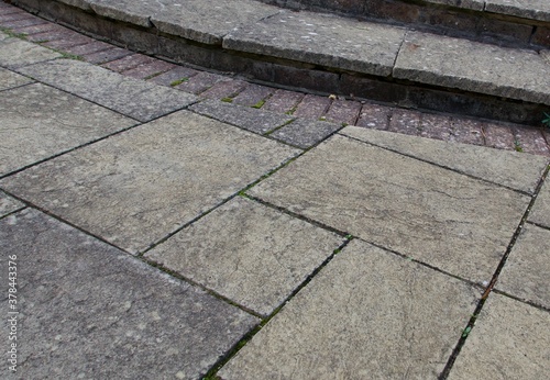 Old weather stained paving patio background with steps and bricks