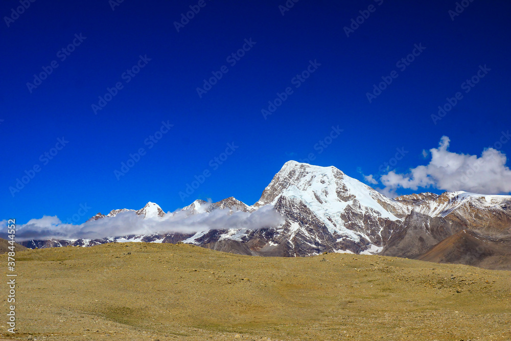 Landscape of deep blue sky and ice capped peaks of himalayan mountains with white clouds during day time