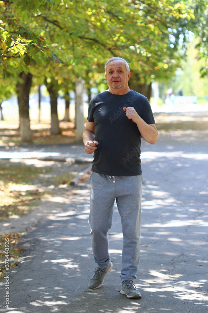 Soft focus. Toning. The gray-haired senior man is engaged in sports walking on the street. Recovery after stroke or heart attack concept. Soft focus. Toning. The gray-haired senior man is engaged in sports walking on the street. Recovery after stroke or heart attack concept.