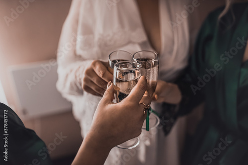 girls in white and green silk robes clink glasses of champagne