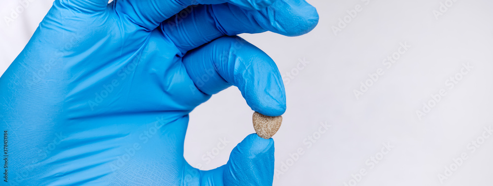 Hands doctor's in medical gloves hold a heart shaped pill. Blue disposable gloves isolated on a white background. Pharmaceutical concept. medicine, research concept Hands doctor's in medical gloves hold a heart shaped pill. Blue disposable gloves isolated on a white background. Pharmaceutical concept. medicine, research concept