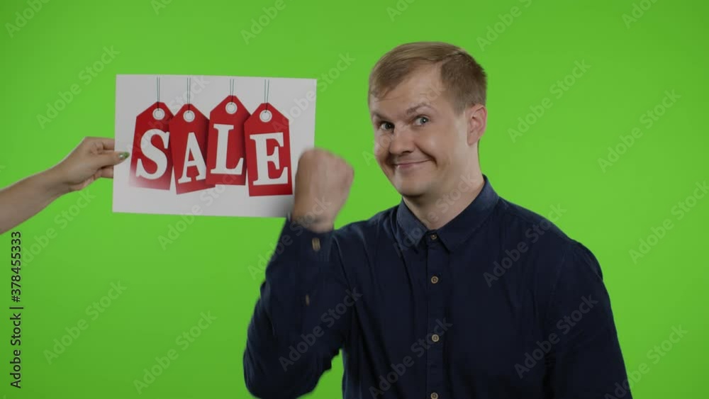 Inscription Sale word appears next to smiling man. Guy showing thumbs up. Shopping on Black Friday Inscription Sale word appears next to smiling man. Guy showing thumbs up. Shopping on Black Friday