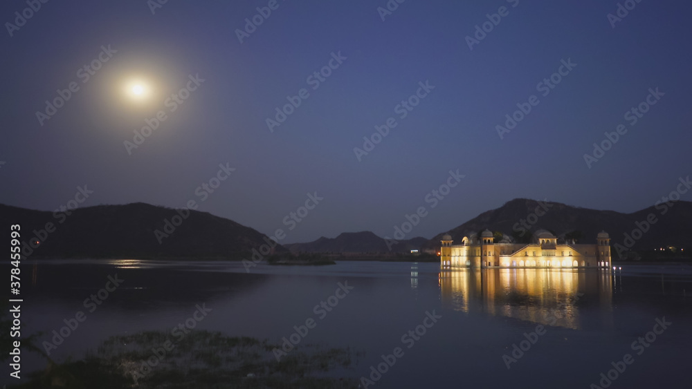 night shot of jal mahal palace and a full moon in jaipur