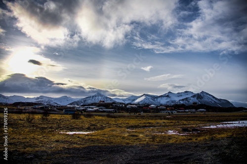 Fototapeta Naklejka Na Ścianę i Meble -  Village surrounded by mountains with white peaks in an Icelandic landscape
