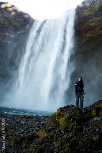 Woman standing in front of a powerful waterfall with mist and wind in Iceland