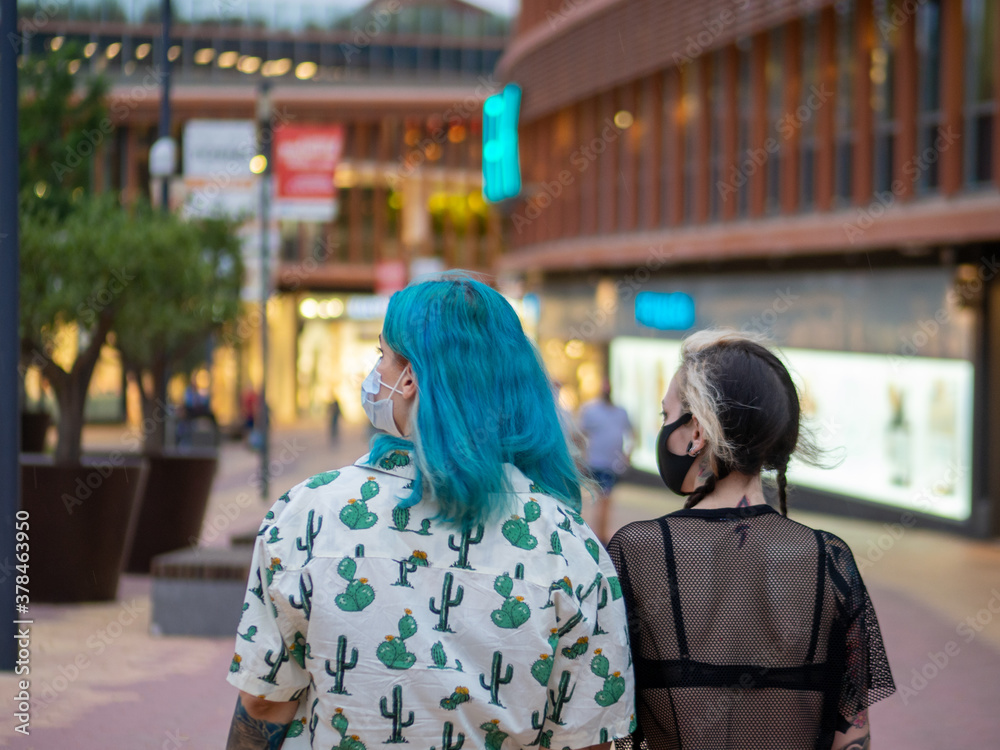 Fototapeta premium Mujeres jóvenes paseando por la calle con tiendas y luces