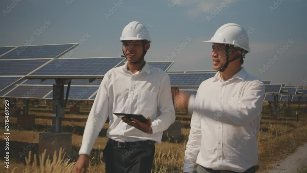Technician and investor walking in Solar cell Farm through field of solar panels checking the panels at solar energy installation.Solar cells will be an important renewable energy of the future. Technician and investor walking in Solar cell Farm through field of solar panels checking the panels at solar energy installation.Solar cells will be an important renewable energy of the future.