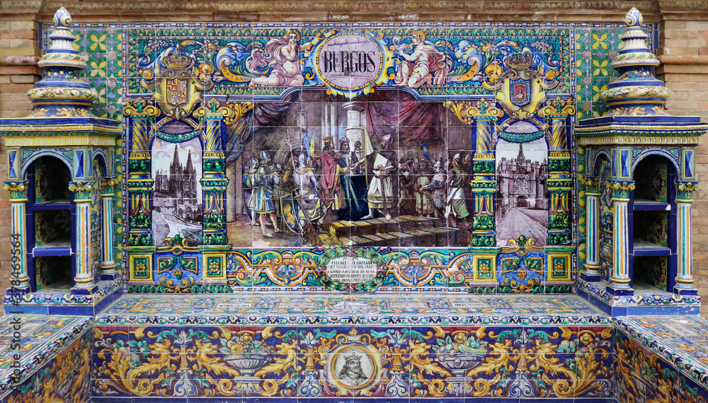 Image with the name of the spanish city of Burgos and a historical scene painted on ceramic tiles - seating benches in Spain Square in Seville