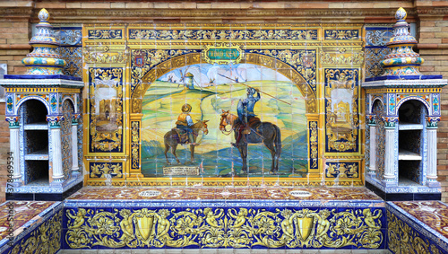 Image with the name of the spanish city of Ciudad Real and a scene of Don Quixote and the windmills painted on ceramic tiles - seating benches in Spain Square in Seville
