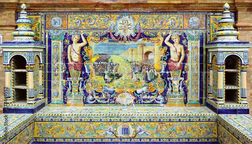 Image with the name of the spanish city of Badajoz and a historical scene painted on ceramic tiles - seating benches in Spain Square in Seville