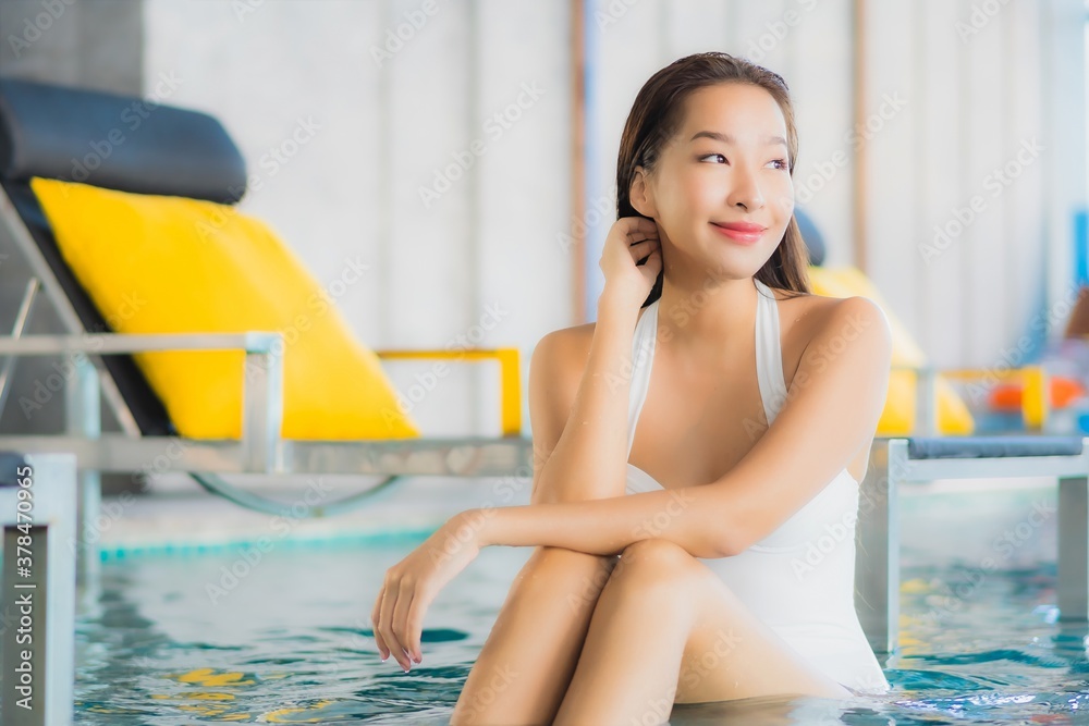 Portrait beautiful young asian woman relax smile around swimming pool in hotel resort