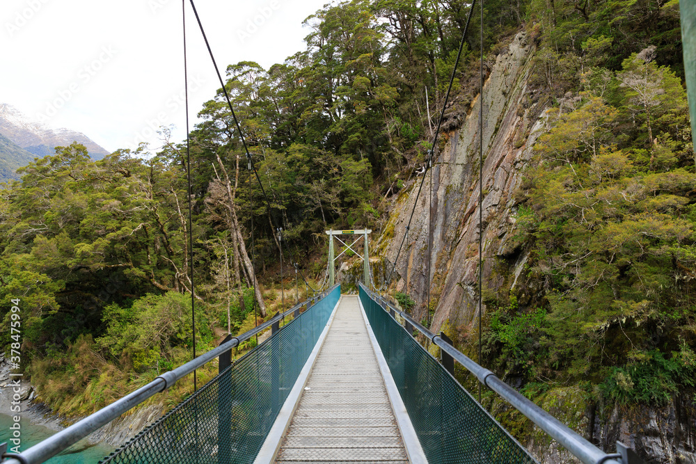 Fototapeta premium Wood bridge with rope for walking in Mount Aspiring National Park, New Zealand.
