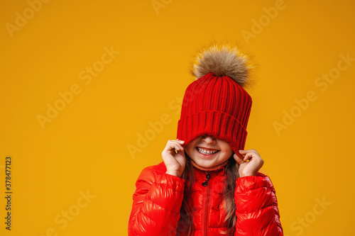 happy, cheerful girl pulls a red knitted hat over her eyes.