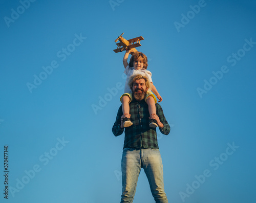 Father carrying his son on shoulders. Father and son playing with toy plane outdoor. Family holiday, parenthood. Fathers day.