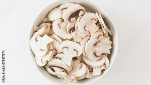 Bowl of fresh row chopped mushrooms close up on whiite background, flat lay