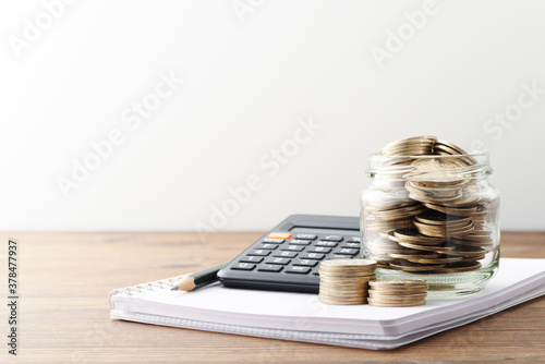 Money and calculator. Calculating personal finance and saving money. Money in jar and household accounts book on wood table. photo