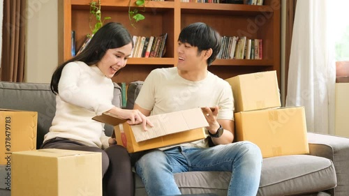 Young asian happiness man and woman help each other open box of goods ordered online.