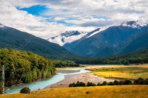 Amazing close-up view at Cameron Flat picturesque landscape in Mount Aspiring National Park, along Makarora River, with snow-capped mountain peaks in the background engulfed in clouds, in New Zealand.