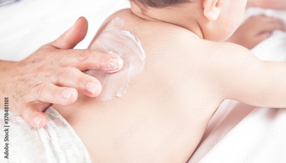 Grandmother applying body cream on her grandson.