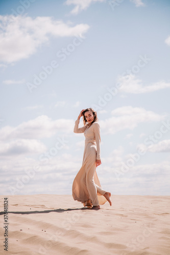 Young  slender girl in beige dress walks in the desert