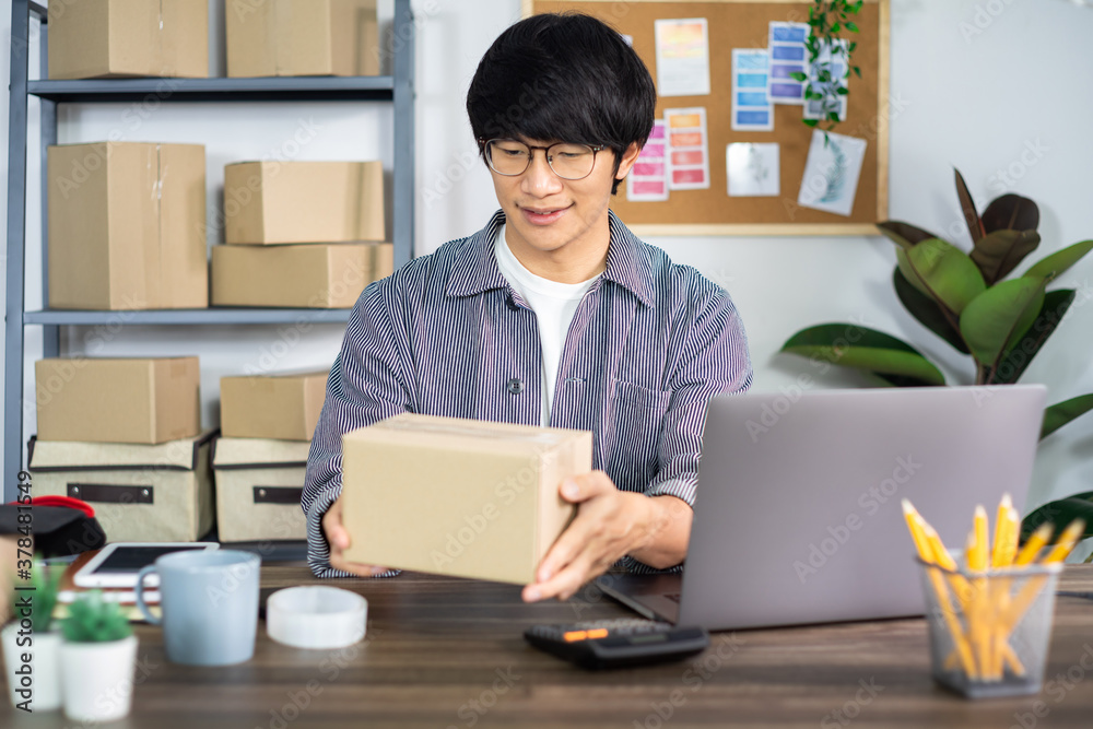 Asian business man startup SME entrepreneur or freelance working in a cardboard box prepares delivery box for customer, Online selling, e-commerce, packaging and shipping concept. Asian business man startup SME entrepreneur or freelance working in a cardboard box prepares delivery box for customer, Online selling, e-commerce, packaging and shipping concept.