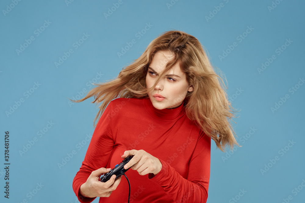 Pretty woman gamepad in hands playing games entertainment consoles to lifestyle blue background red jacket Pretty woman gamepad in hands playing games entertainment consoles to lifestyle blue background red jacket