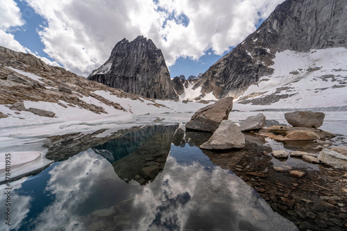 Reflection in glacier lake of snow, cloudy sky and Bugaboo spire in Bugaboos provincial park, British Columbia, Canada in landscape photo