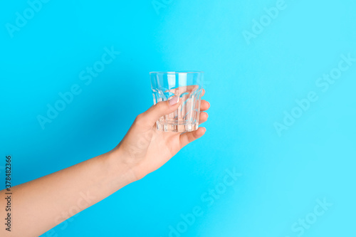 Hand with empty glass on color background