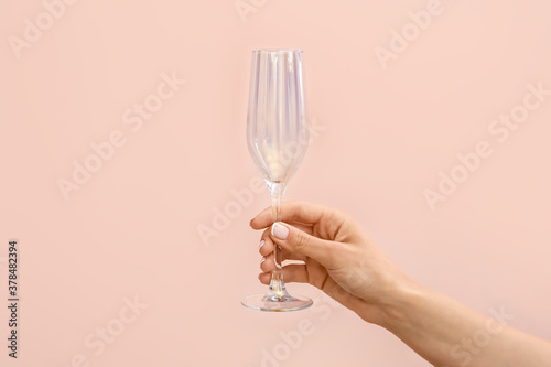 Hand with empty glass on color background