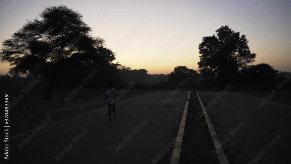 Man walking on the highway at sunset time Man walking on the highway at sunset time