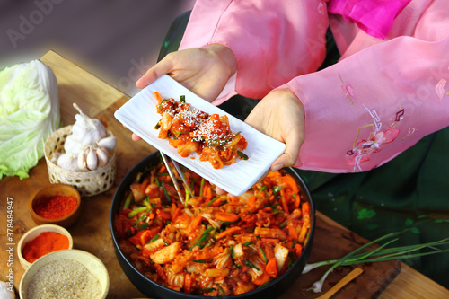 top view Korean woman in national costume showing her kimchi in white ceramic dish