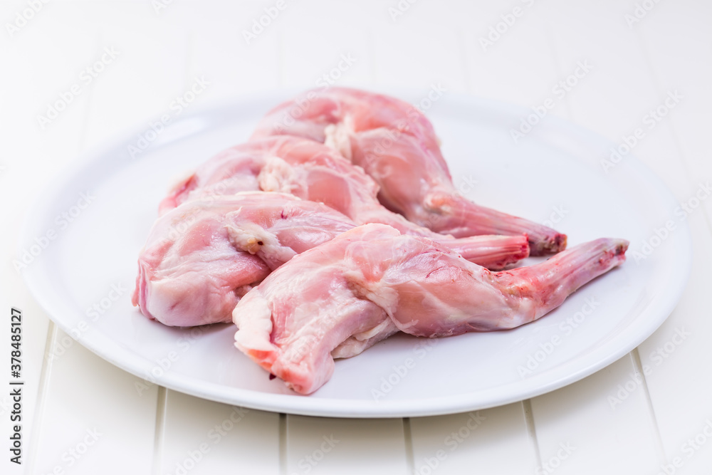 Raw rabbit legs on white plate