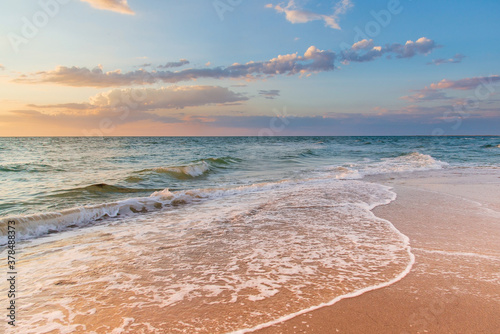 Fototapeta Naklejka Na Ścianę i Meble -  White foam waves on the sand at sunset in the sea