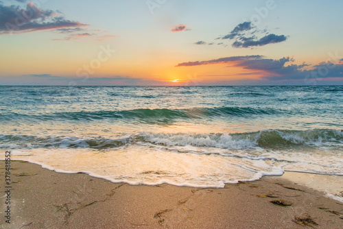 White foam waves on the sand at sunset in the sea
